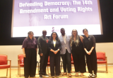 Rep. Mejia and democracy advocates pose on stage in front of a screen reading "Defending Democracy: The 14th Amendment and Voting Rights Act Forum."