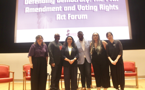 Rep. Mejia and democracy advocates pose on stage in front of a screen reading "Defending Democracy: The 14th Amendment and Voting Rights Act Forum."